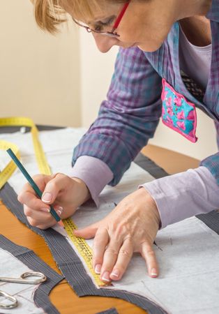 Dressmaker drawing tailor pattern on the table