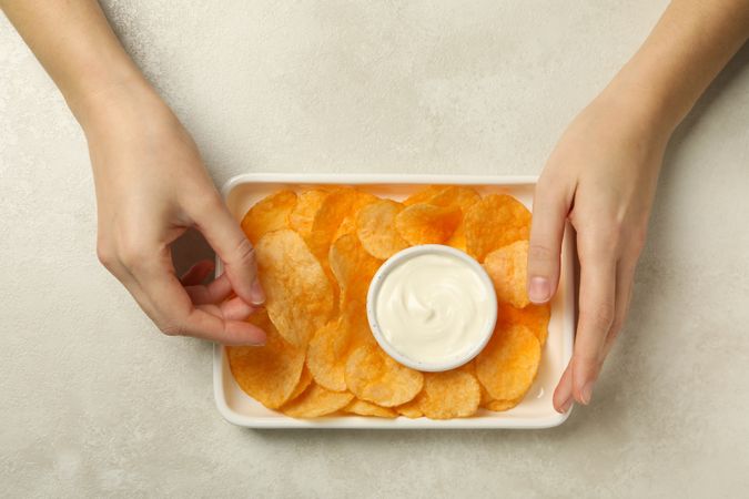 Potato chips in a bowl with sauce on a light background