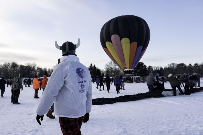 Hudson, WI, USA - February 8th, 2020: Man in Viking hat looking at hot balloon in the winter
