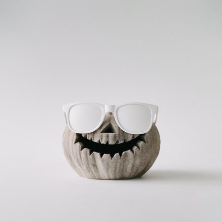 Pumpkin skull with sunglasses on light wall