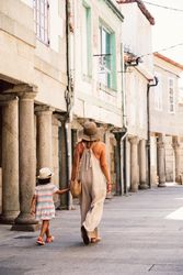 Mother and daughter walking in street along ancient building