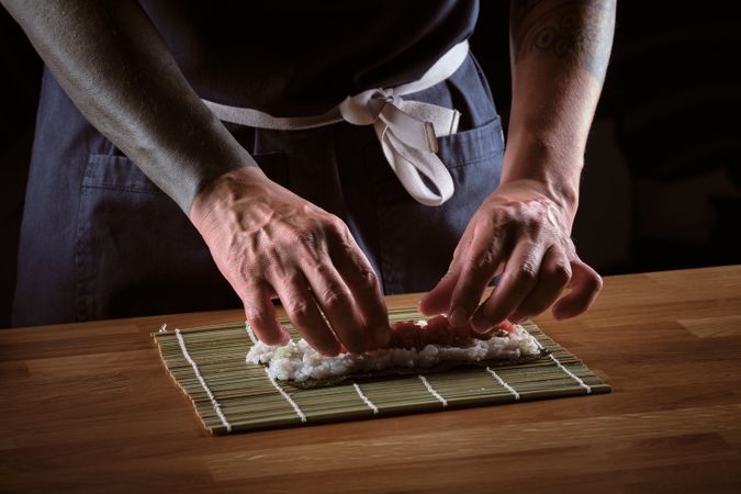 Male shushi man hands preparing different pieces of makis