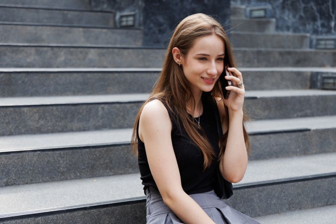 Woman sitting on stairs and talking on mobile phone