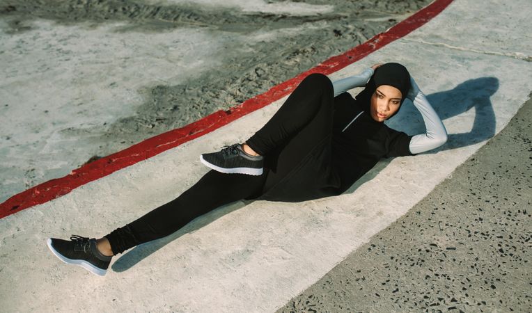 Sports woman in hijab doing bicycle crunch workout outdoors