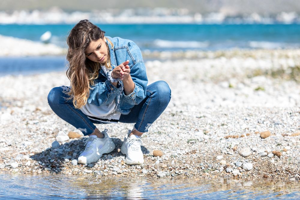 Young woman playing with water on shore