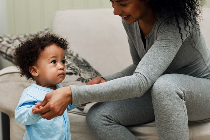 Woman holding her toddler son up as he walks