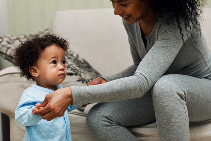 Woman holding her toddler son up as he walks