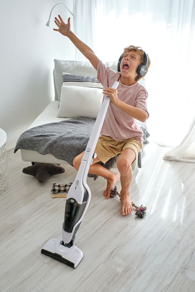 Boy with vacuum cleaner singing loudly