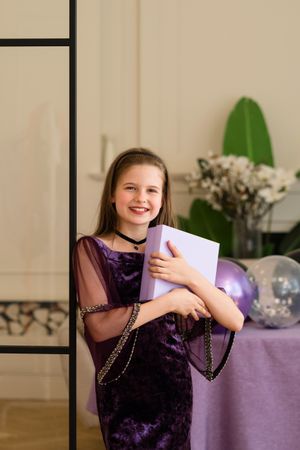 Smiling girl holding gift box at birthday party.