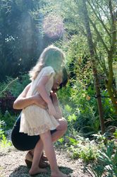 Smiling mother and young daughter outside on garden path