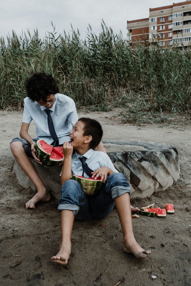Little boys playing while eating watermelon on beach