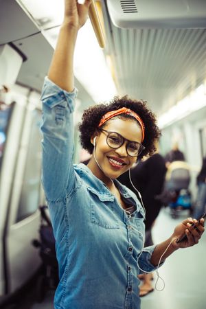 Woman holding cell phone and smiling on public transport