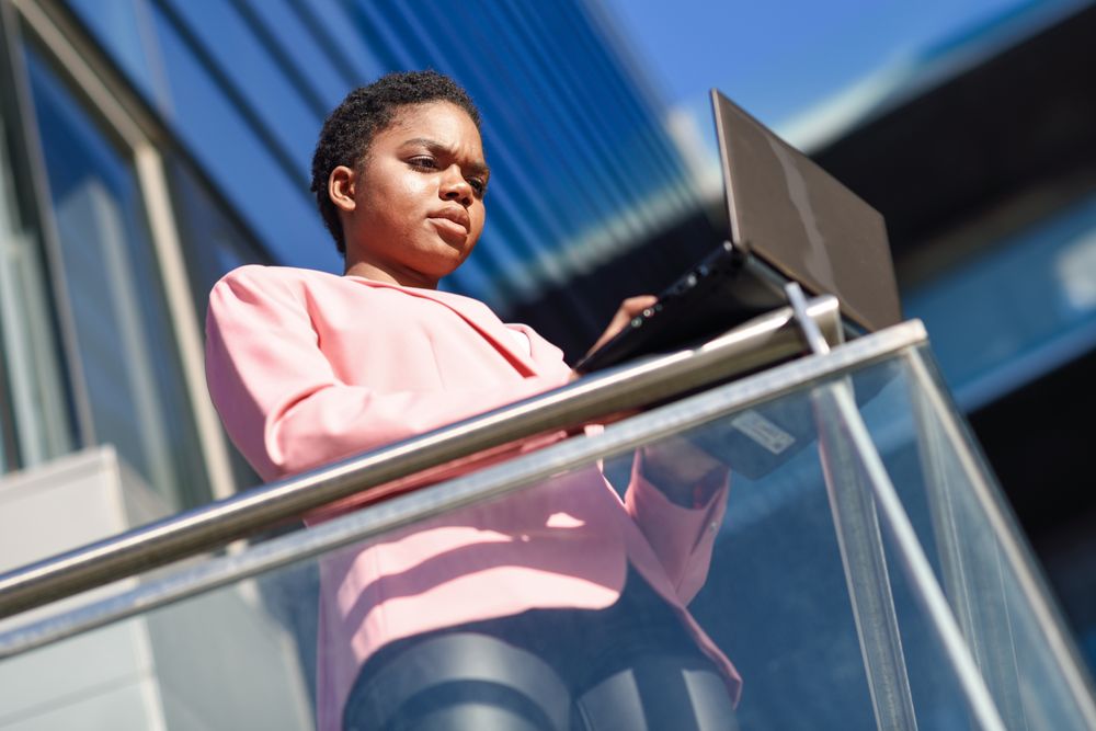 Serious woman checking laptop balanced on metal rail