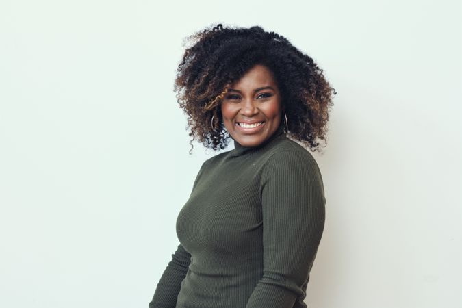 Portrait of smiling Black woman in green turtleneck