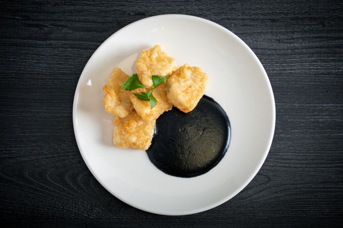 Hake breaded with squid cream in plate