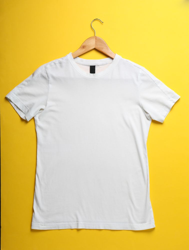 Hanger with blank plain t-shirt on yellow background, space for text