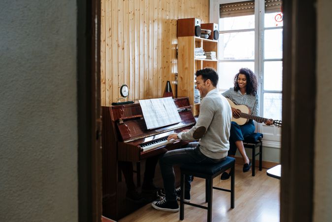 Man playing piano near woman playing guitar in studio