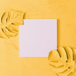 Yellow painted leaves, on yellow background with paper