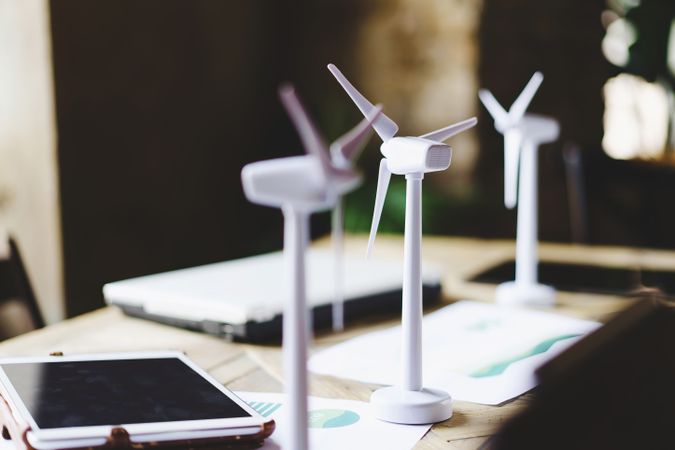 Close up of wind turbines on a table with data sheets, tablet and laptop computer plan blueprints