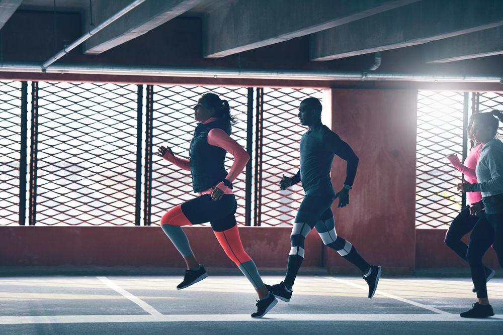 Group of athletic people doing springs near window