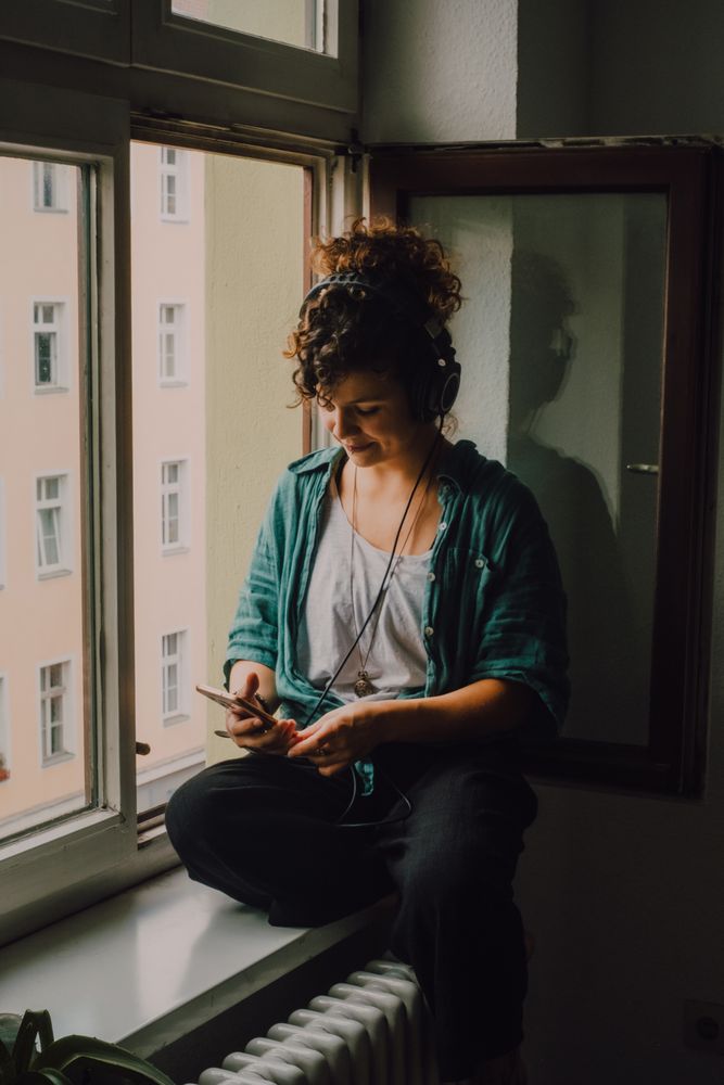 Cheerful woman in headphones using smartphone at home