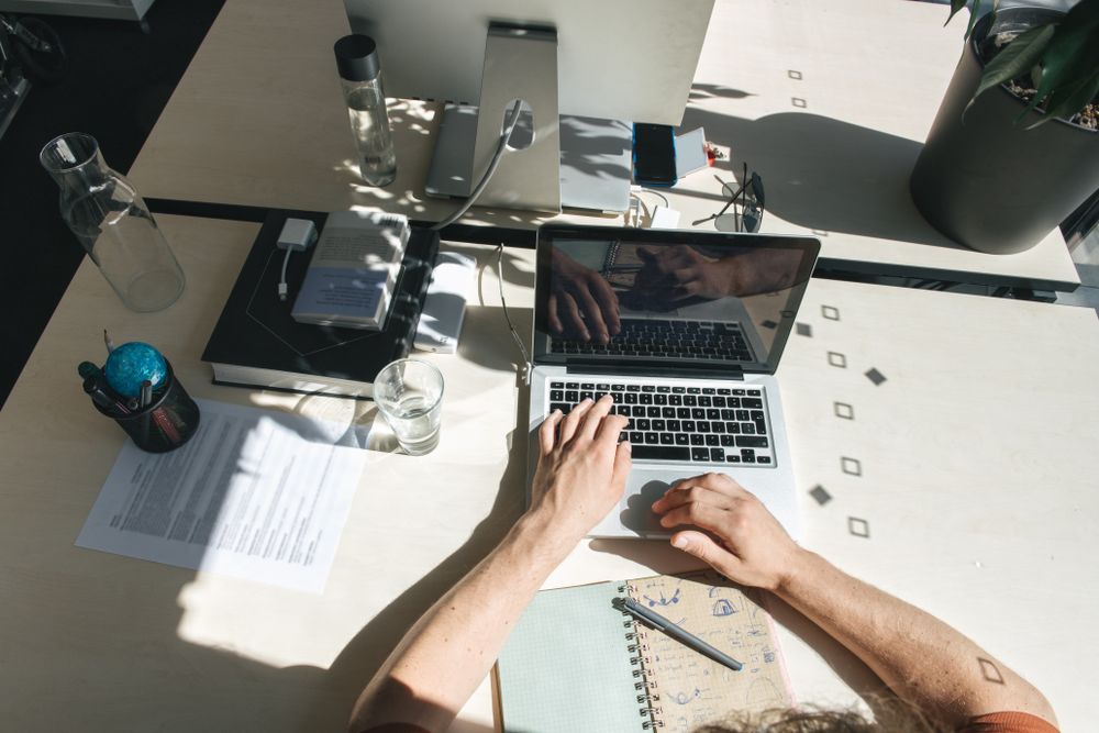 Crop man using laptop at workplace