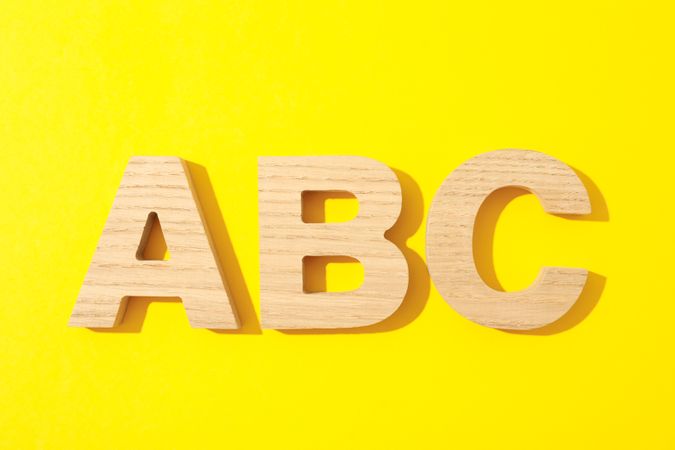 Wooden letters of English alphabet on color background, space for text