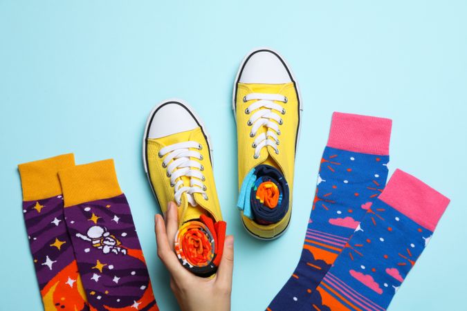 Socks, female hand and sneakers with socks on blue background