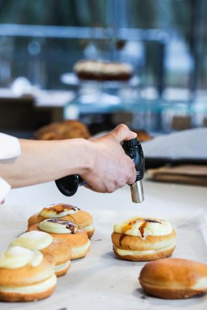 Crop cook burning cream on dessert with gas burner in bakery