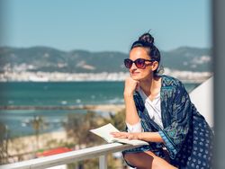 Stylish woman with book admiring seascape