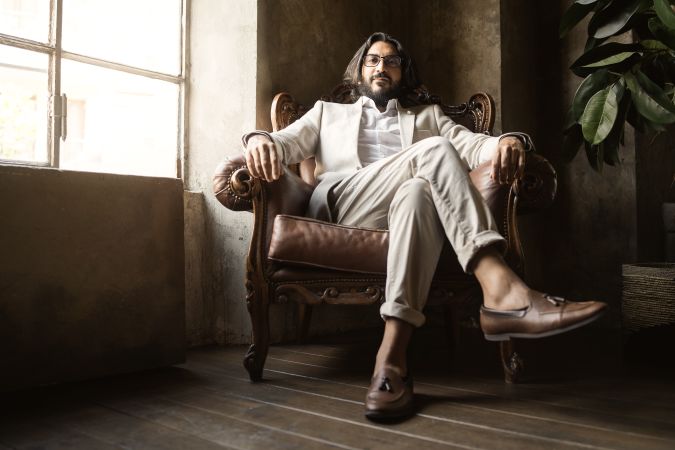 Portrait of proud Middle-Eastern businessman wearing eyeglasses sitting comfortably in an armchair