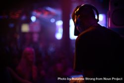 Dark image of man in headphones playing at night club 4dLaD4
