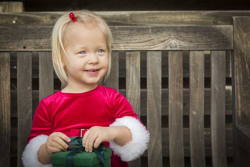 Adorable Little Girl Unwrapping Her Gift on a Bench