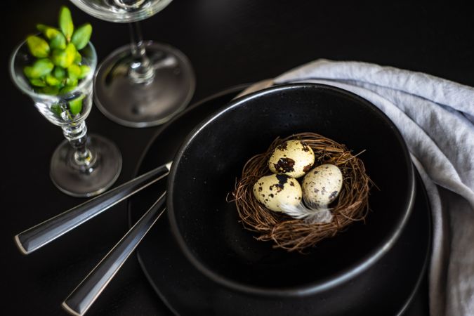 Easter table setting with nest and eggs in dark bowl