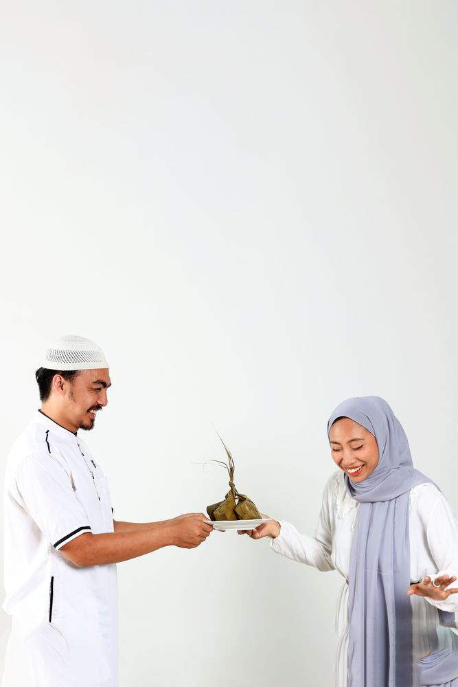 Asian Muslim Female and Male Holding White Plate with Ketupat for Eid Mubarak Celebration
