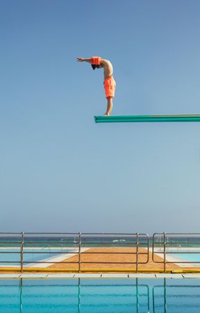 Boy standing on high dive spring board preparing to dive