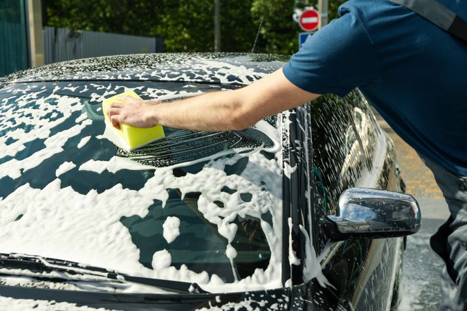 Man wipes the car with a sponge. Car wash. Clear car concept