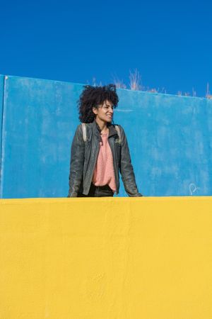 Black woman with afro hair leaning against brightly colored wall