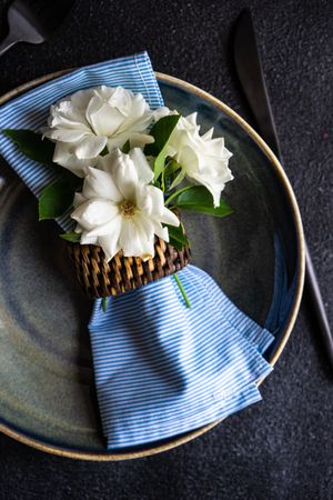 Minimalistic table setting with flower on plate with blue napkin
