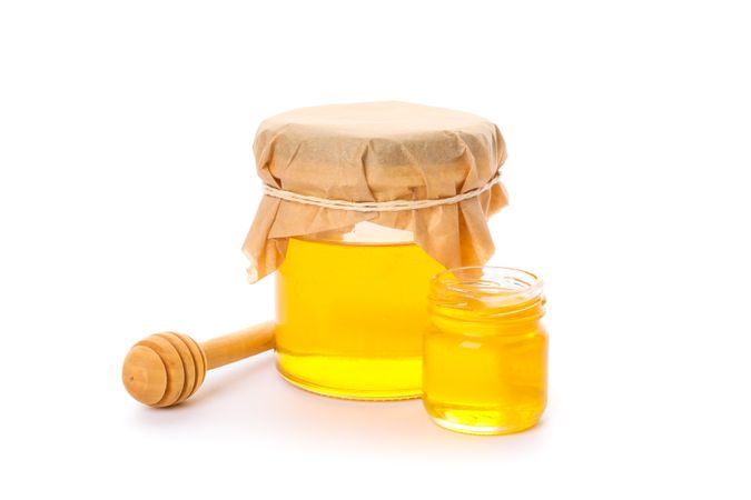 Dipper and glass jars with honey isolated on plain background