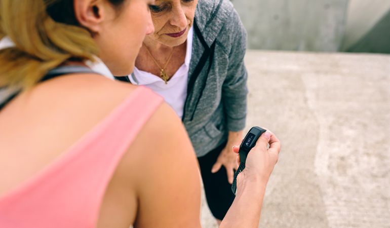 Older woman looking smart watch with her coach