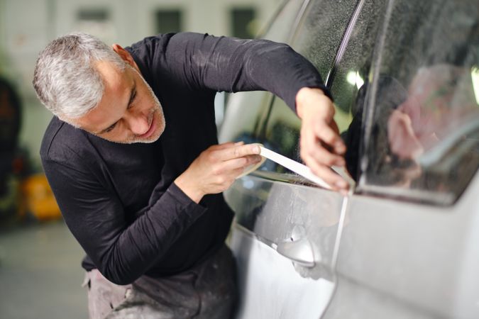 Mechanic putting protective tape on car