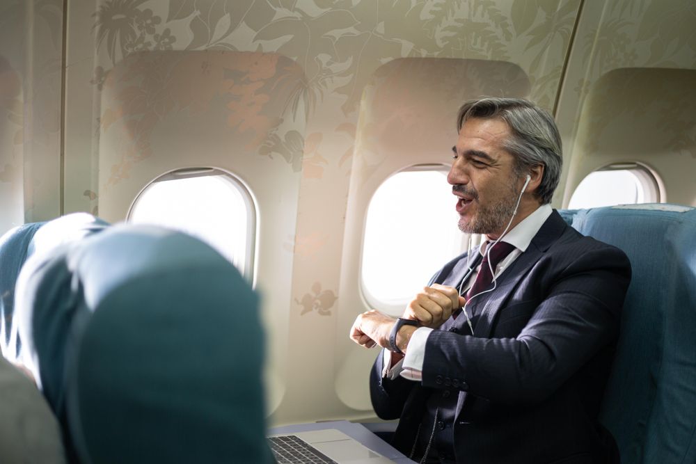 Man in suit on flight using laptop while talking