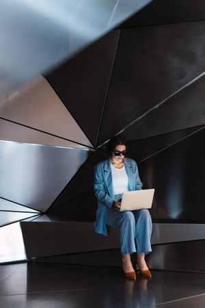 Woman in sunglasses browsing laptop in studio