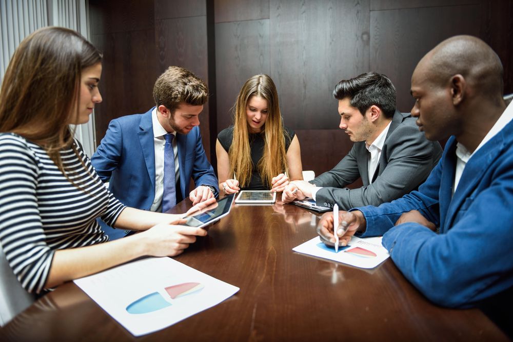Corporate workers together in a meeting using pie charts and digital tablets