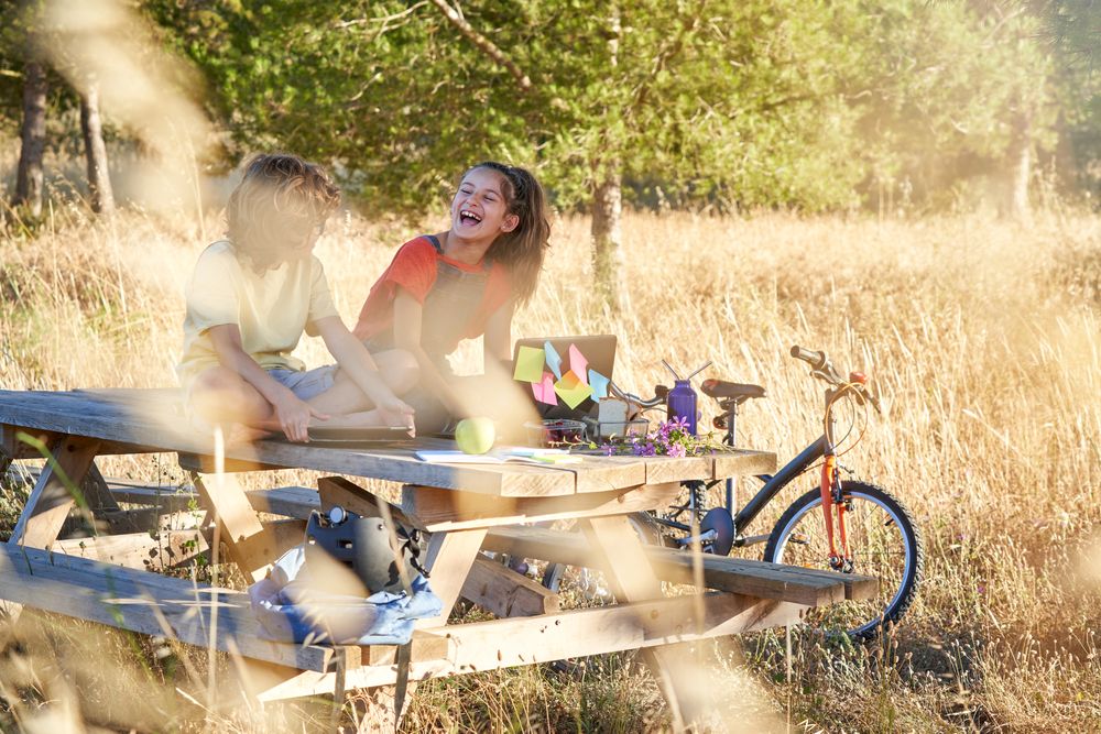 Children having fun and using gadgets in recreation area in natu