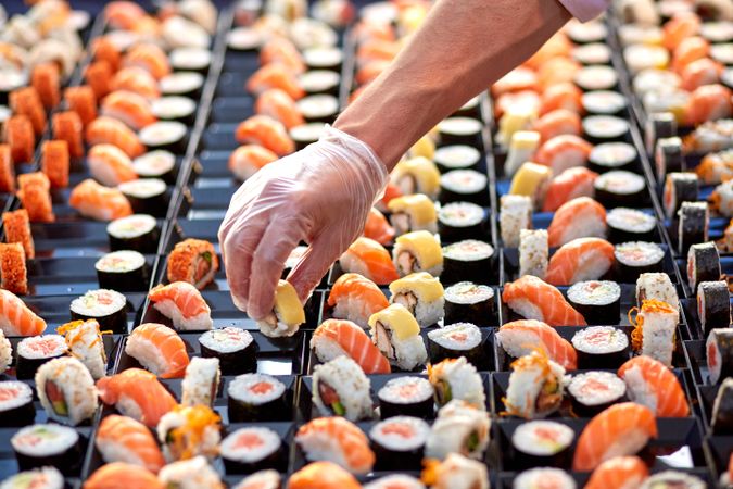 Crop seller at counter with sushi in market
