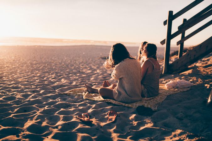 Group of young women sitting in the sand at the beach