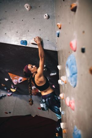 Focused climber rock climbing at indoor rock wall