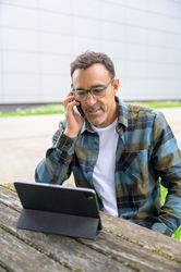 Smiling man talking on phone and using laptop